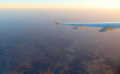 Naklejka premium Scenic view from an airplane wing during sunset over rolling hills and valleys