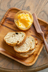 Artisan Bread Slices with Golden Butter and Wooden Spreader on a Rustic Tray, slices of bread with butter on wooden plate, food closeup