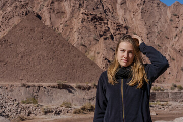 Young woman posing in front of pyramid-shaped desert hill