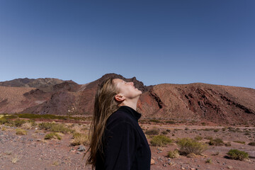 Woman looking up in red desert mountain landscape