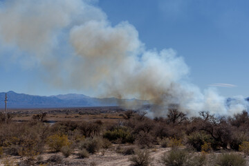 Smoke rising from bushfire in arid desert valley landscape