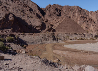 Pyramid-shaped hill in rocky desert valley with winding river