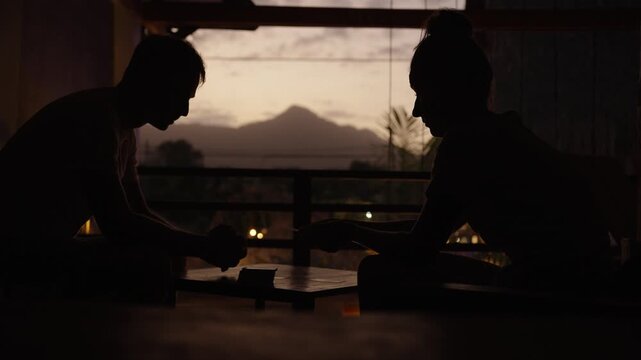 Travelers playing cards in Palomino, Colombia, scenic silhouette dawn moment, mountain top in background, backlight setting
