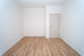 Empty room with white clean walls and light wood laminate floor,space under the cabinet. New apartment interior design concept for renovation or real estate.