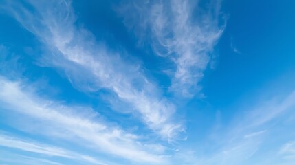 Wispy cirrus clouds drift across a vast expanse of bright blue sky on a clear day