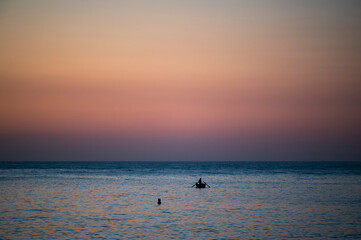 Fototapeta premium Lonely fisherman in the sea at sunrise, Acitrezza