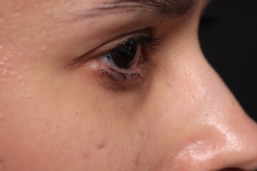 Fototapeta premium Sad woman crying on black background, closeup