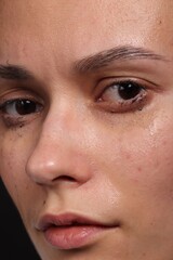 Fototapeta premium Sad woman crying on black background, closeup