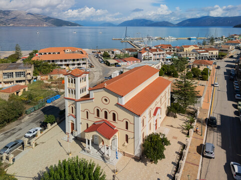 Fototapeta Aerial view of a church with terracotta roof tiles stands prominently against the backdrop of the Ionian Sea and distant mountains, Sami, Cephalonia, Greece.