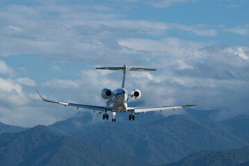 Landing of a private plane at Batumi Airport against a backdrop of mountains and a cloudy sky.