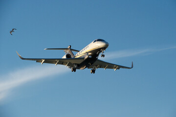 A private jet approaches the airfield against a backdrop of a partly cloudy sky. Airplane in the blue sky with white clouds.