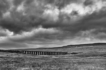 Ribblehead Viaduct beneath dramatic storm clouds in black and white