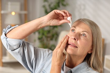Fototapeta premium Senior woman applying eye drops at home