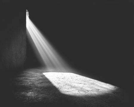 Dramatic light streams through an opening into a dark space
