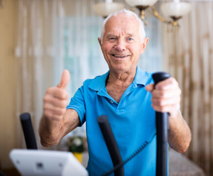 Senior man with elliptical trainer at home - Powered by Adobe