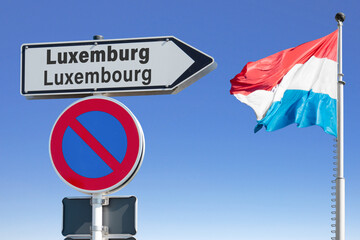 Wegweiser Luxemburg (Luxembourg) mit Nationalflagge und einem Verkehrsschild, eingeschränktes Halteverbot