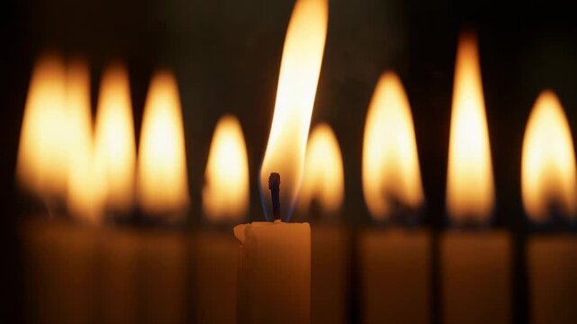 Flickering central wax candle flame dancing in darkened room, responding to subtle air currents