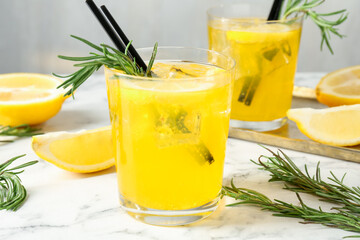 Glasses of tasty cocktails with lemon and rosemary on white marble table, closeup