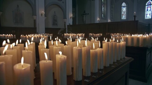 When shot begins camera panning across votive candles on table in church revealing smoke and arches