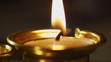 Flickering flame burning cotton wick on brass oil lamp in dim room, with melted oil ripples - Powered by Adobe