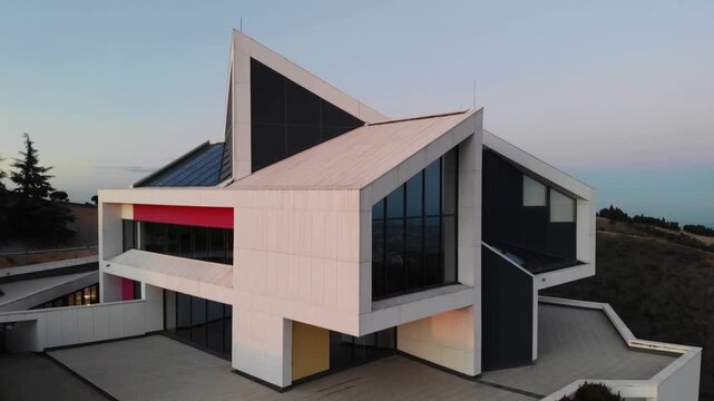 After liftoff, panning drone capturing white house on hillside at dusk with windows and red balcony