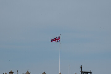 A clear view of the Union Jack flag waving against a blue sky, symbolizing British identity and heritage. © Svetlana