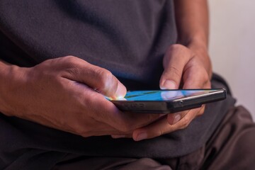 A man using smartphone to access online mobile banking or open social media application.