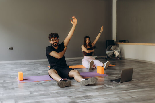 Couple doing online fitness class stretching at home