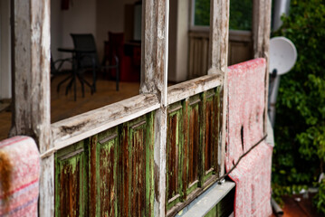 A traditional wooden balcony with intricate carvings overlooks the historic cityscape of Tbilisi, Georgia. A patterned rugs hangs over the railing, adding a touch of cultural authenticity.
