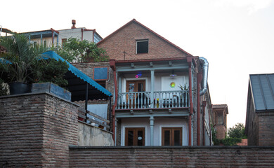 A charming brick building with wooden balconies and a red-tiled roof, located in the heart of Tbilisi. The architecture reflects traditional Georgian style with modern touches..