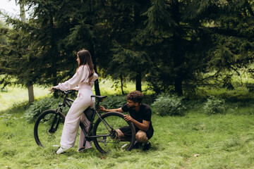 Man helping woman fixing bicycle in park