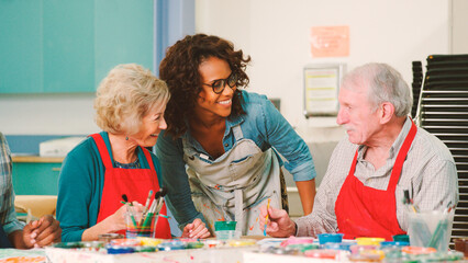 Group Of Retired Seniors Attending Art Class In Community Centre With Teacher