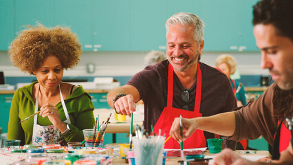 Group Of Mature Adults Attending Art Class In Community Centre With Teacher
