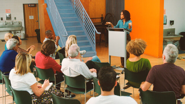 Woman Speaking At Group Neighborhood Meeting In Community Center