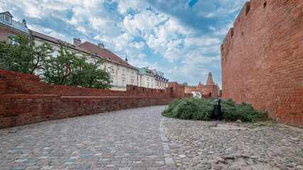 The defensive walls of Warsaw's old town. Brick walls, townhouses in the background. The capital of Poland. Podwale Street. The Barbican.
