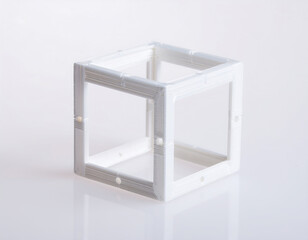 A small, intricate, white 3D-printed lattice cube, levitating and slowly rotating. Isolated against a brilliant white background