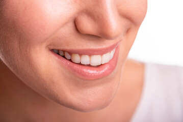 Close-up image of a smiling woman showing her white teeth and natural lips, representing happiness, confidence, and dental health.