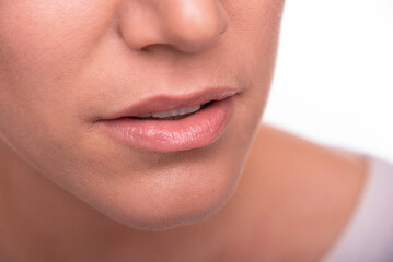 A woman's mouth and lower face, emphasizing natural lips and skin texture, is presented on a white background.