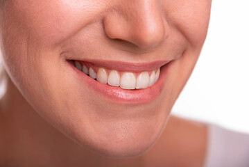 Close-up image of a smiling woman showing her white teeth and natural lips, representing happiness, confidence, and dental health.