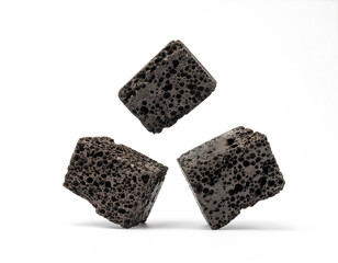 Three pieces of dark, porous lava rock, used in aquariums Isolated on a stark white background