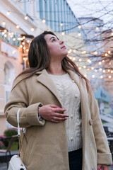 young woman standing outdoors on night neon street cafe illuminated for new year holding phone