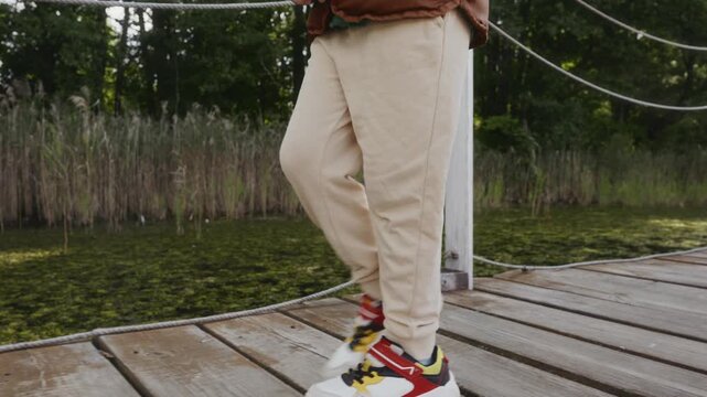Close-up of sneakers stepping on wooden pier. Represents first independent steps, confidence and growth. High quality 4k footage