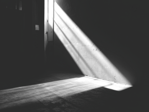 Stark beam of light slashes through dark, aged structure, casting shadows
