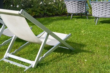 Empty lawn deck chair on grass lawn or park, relaxation on summer or spring sunny day. Hotel space, traveling and vacations on resorts. Garden furniture