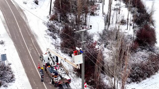 Workers repairing power lines on a snowy day, ensuring energy flow despite harsh winter conditions.