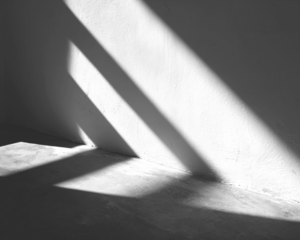 Stark shadow play on a gray corner, creating abstract patterns with light and dark