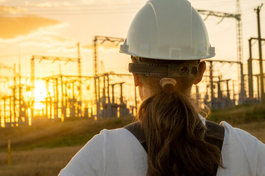 Sunset view of an engineer at a power station with electricity pylons in the background