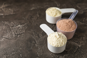 Protein powder. A spoonful of protein powder on a table. Different flavors of whey protein powder. Sports nutrition concept. Gym. Amino acid food supplement, creatine powder. Copy space.