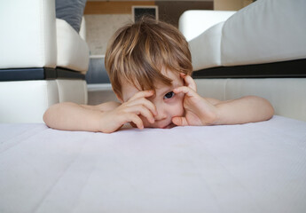 little three-year-old boy plays  on the sofa at home