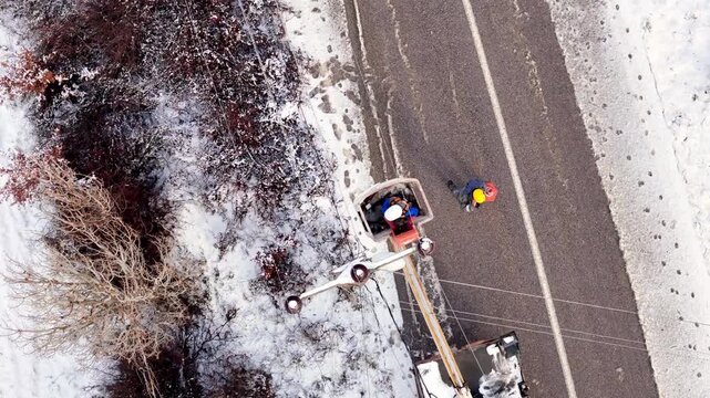 Workers repairing power lines on a snowy day, ensuring energy flow despite harsh winter conditions.